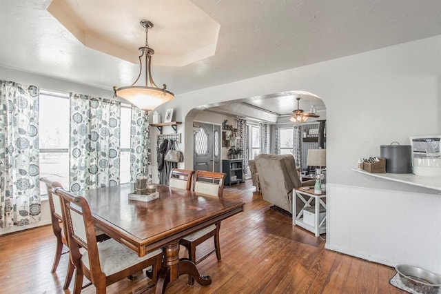 1505 N Piedmont Rd, Yukon, OK 73099 - dining space featuring arched walkways, a raised ceiling, wood-type flooring, wainscoting, and ceiling fan