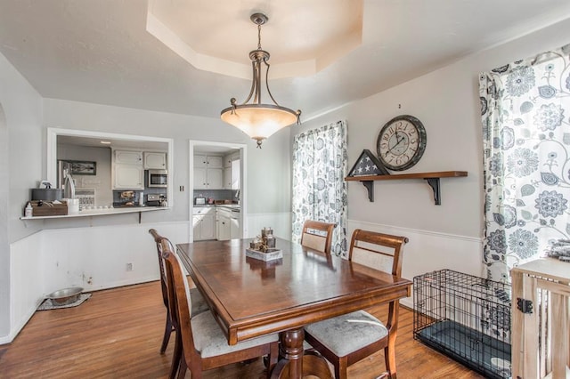 1505 N Piedmont Rd, Yukon, OK 73099 - dining area with wood finished floors, a tray ceiling, and wainscoting