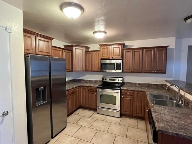 1400 Hillside Ter, Blanchard, OK 73010 - kitchen featuring appliances with stainless steel finishes, a sink, dark countertops, light tile patterned flooring, and a peninsula