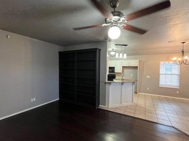414 SE 7th St, Lexington, OK 73051 - kitchen with a textured ceiling, black microwave, a ceiling fan, light wood-type flooring, and white cabinetry