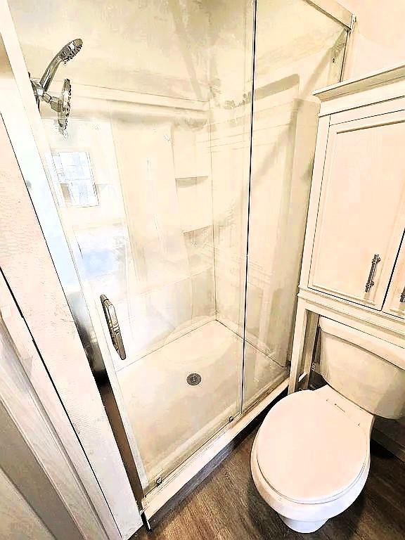 716 S 13th St, Frederick, OK 73541 - bathroom with wood finished floors, toilet, and a shower stall