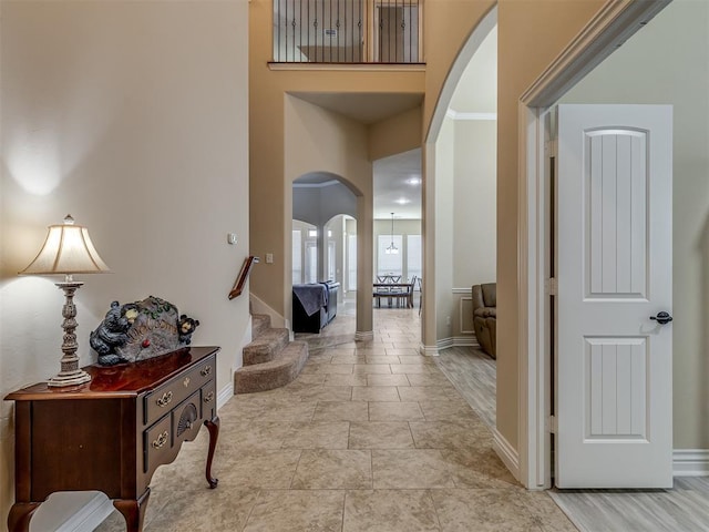 2500 Cordgrass Ln, Edmond, OK 73013 - hallway with arched walkways, baseboards, stairs, and a towering ceiling