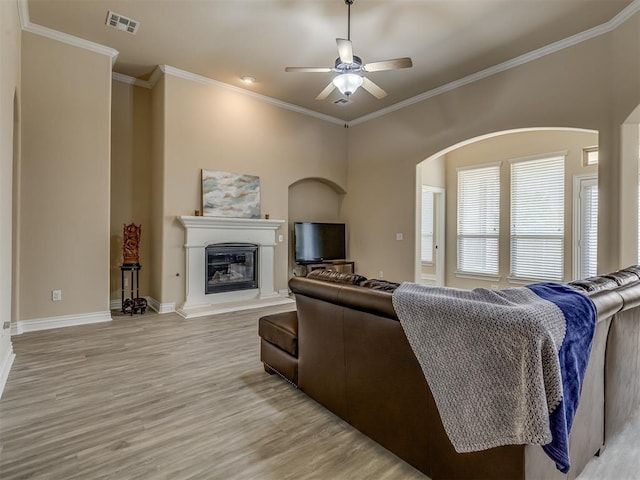 2500 Cordgrass Ln, Edmond, OK 73013 - living room featuring light wood-style floors, a ceiling fan, ornamental molding, a glass covered fireplace, and baseboards