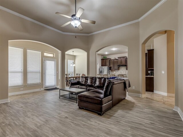 2500 Cordgrass Ln, Edmond, OK 73013 - living room with arched walkways, light wood-style flooring, a ceiling fan, crown molding, and baseboards