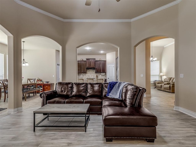 2500 Cordgrass Ln, Edmond, OK 73013 - living area with arched walkways, ornamental molding, a ceiling fan, baseboards, and light wood-type flooring