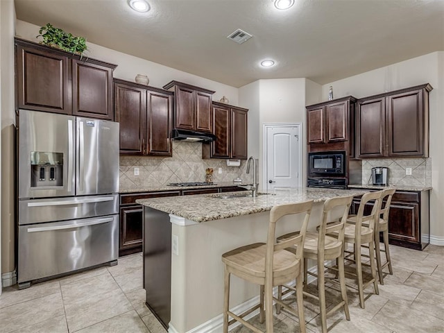 2500 Cordgrass Ln, Edmond, OK 73013 - kitchen featuring stainless steel appliances, a sink, under cabinet range hood, a breakfast bar, and decorative backsplash