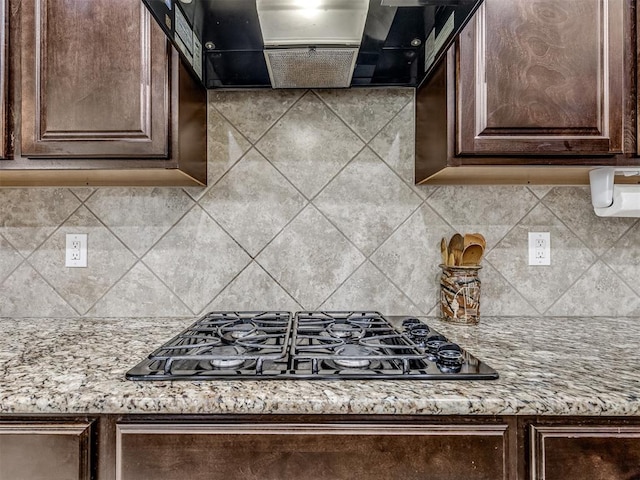 2500 Cordgrass Ln, Edmond, OK 73013 - kitchen with black gas cooktop, dark brown cabinets, ventilation hood, decorative backsplash, and light stone counters