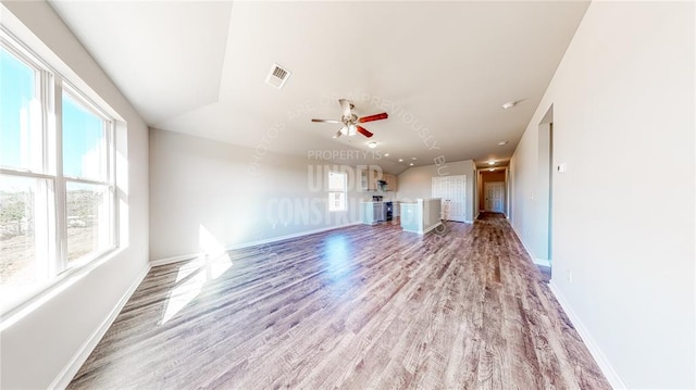 11817 NW 97th St, Yukon, OK 73099 - unfurnished living room featuring healthy amount of natural light, light wood-type flooring, and baseboards