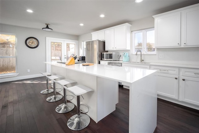 11000 Magnolia Park, Oklahoma City, OK 73120 - kitchen featuring a center island, a sink, a kitchen breakfast bar, appliances with stainless steel finishes, and white cabinetry