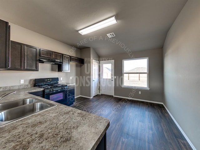 3909 S Ravine St, Stillwater, OK 74074 - kitchen with black gas range oven, a sink, under cabinet range hood, baseboards, and dark wood-style floors