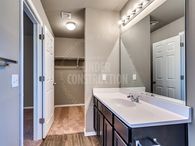 3909 S Ravine St, Stillwater, OK 74074 - bathroom featuring vanity, wood finished floors, baseboards, and a walk in closet