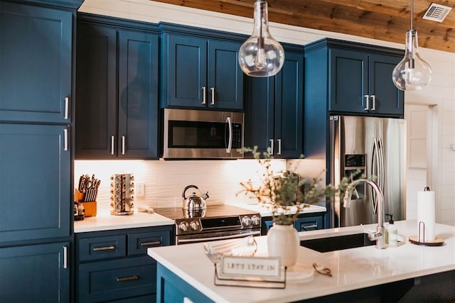 192 Grape Trl, Broken Bow, OK 74728 - kitchen featuring stainless steel appliances, blue cabinets, a sink, light countertops, and decorative light fixtures