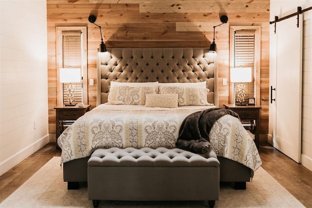 192 Grape Trl, Broken Bow, OK 74728 - bedroom featuring a barn door, wood walls, baseboards, and wood finished floors