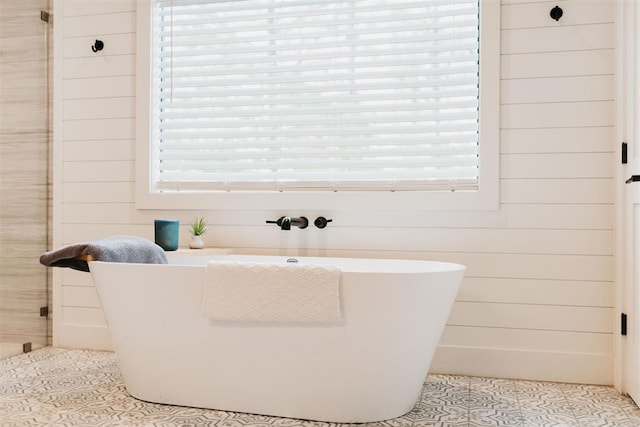 192 Grape Trl, Broken Bow, OK 74728 - bathroom featuring tile patterned floors, healthy amount of natural light, a freestanding tub, and wooden walls