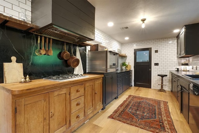 300 E Federal St, Shawnee, OK 74804 - kitchen with wood counters, wall chimney range hood, black dishwasher, stainless steel gas cooktop, and light wood finished floors