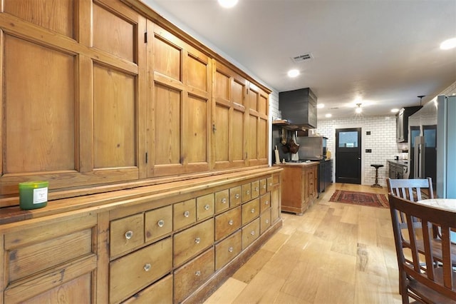 300 E Federal St, Shawnee, OK 74804 - kitchen featuring light wood-style floors, brown cabinetry, high end fridge, wall chimney range hood, and recessed lighting
