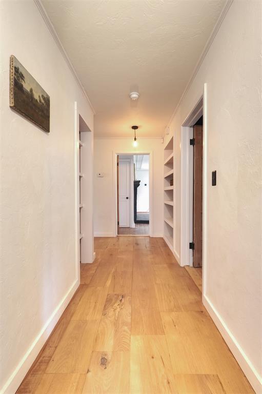 300 E Federal St, Shawnee, OK 74804 - hall with light wood finished floors, crown molding, built in shelves, and baseboards