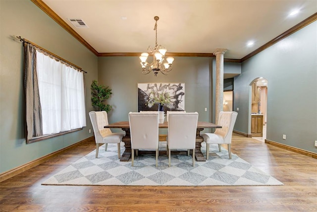 1918 Winding Ridge Rd, Edmond, OK 73034 - dining room with ornamental molding, a chandelier, wood finished floors, decorative columns, and arched walkways