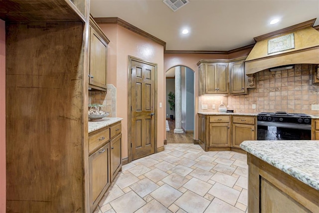 1918 Winding Ridge Rd, Edmond, OK 73034 - kitchen with gas stove, arched walkways, tasteful backsplash, crown molding, and premium range hood