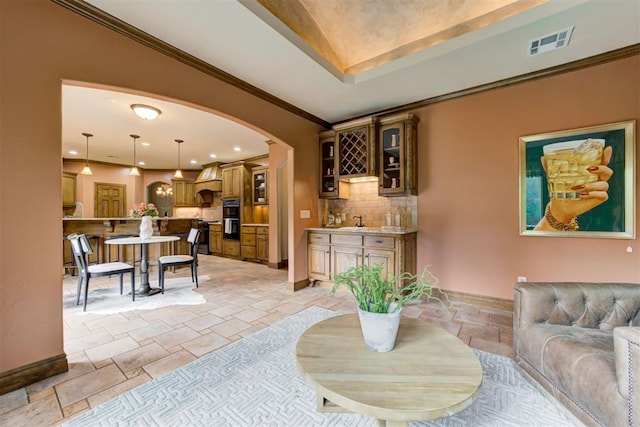 1918 Winding Ridge Rd, Edmond, OK 73034 - living area featuring stone tile floors, arched walkways, bar with sink, ornamental molding, and recessed lighting