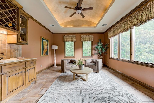 1918 Winding Ridge Rd, Edmond, OK 73034 - living area featuring stone tile floors, a raised ceiling, and a ceiling fan