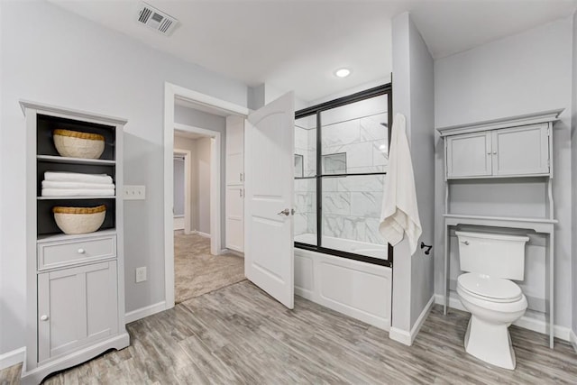 1918 Winding Ridge Rd, Edmond, OK 73034 - bathroom with wood finished floors and bath / shower combo with glass door