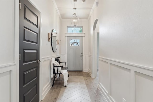 18813 Windy Way Rd, Edmond, OK 73012 - entryway featuring a decorative wall, crown molding, arched walkways, wainscoting, and light wood-style floors
