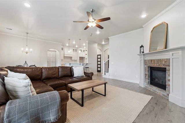 18813 Windy Way Rd, Edmond, OK 73012 - living area with arched walkways, ceiling fan, a fireplace, light wood finished floors, and crown molding