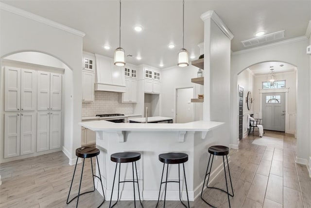 18813 Windy Way Rd, Edmond, OK 73012 - kitchen with open shelves, crown molding, a breakfast bar, arched walkways, and light countertops