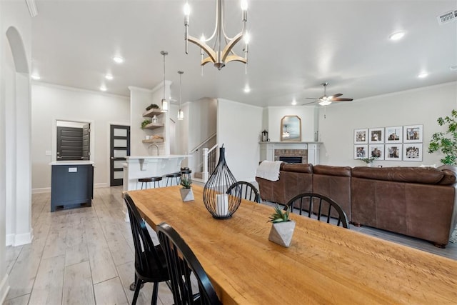 18813 Windy Way Rd, Edmond, OK 73012 - dining space featuring ceiling fan, a fireplace, crown molding, recessed lighting, and light wood-style flooring