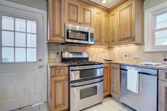2721 NW 45th St, Oklahoma City, OK 73112 - kitchen with appliances with stainless steel finishes, light tile patterned flooring, light stone countertops, and decorative backsplash