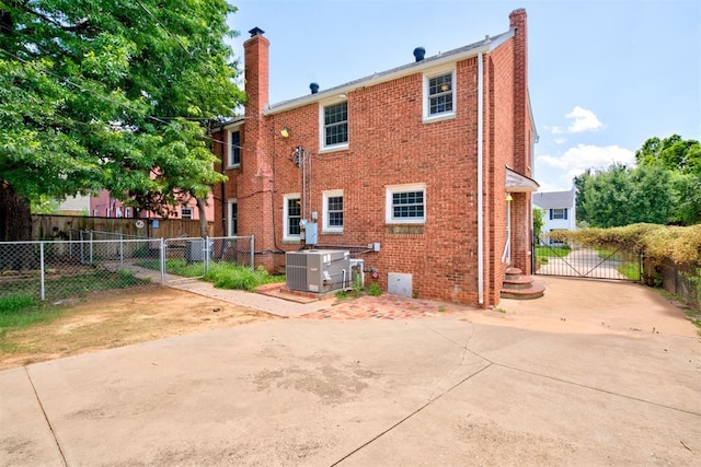 2721 NW 45th St, Oklahoma City, OK 73112 - rear view of house with a chimney, a gate, and brick siding