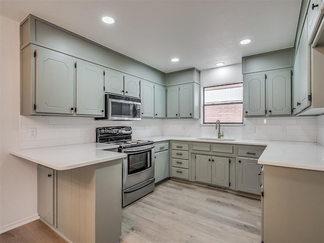 4709 Wilcox Ln, Yukon, OK 73099 - kitchen with a sink, appliances with stainless steel finishes, a peninsula, light wood-style flooring, and tasteful backsplash