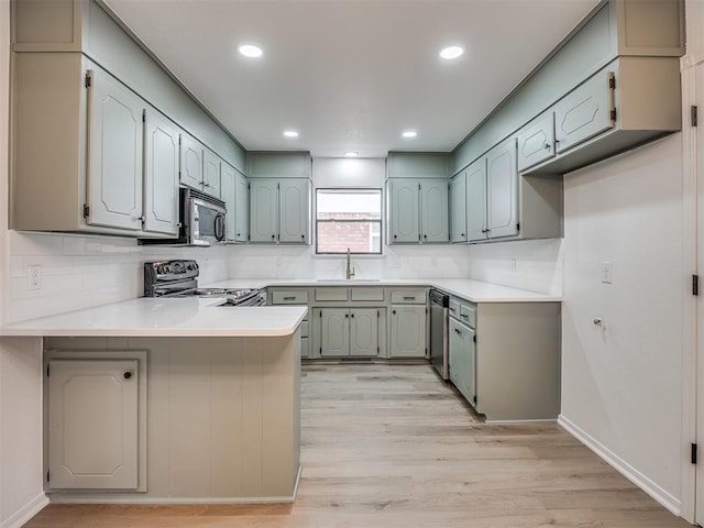 4709 Wilcox Ln, Yukon, OK 73099 - kitchen with stainless steel appliances, a peninsula, a sink, backsplash, and light wood-style flooring