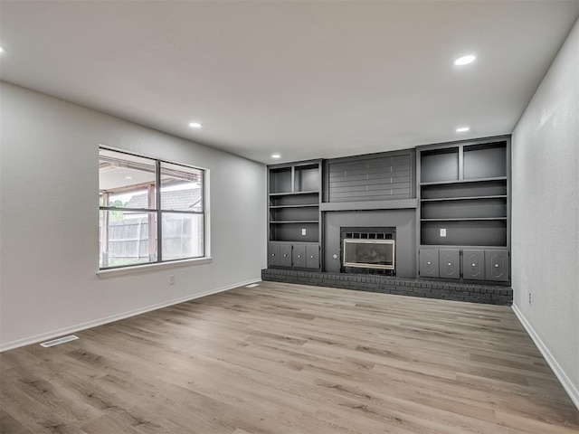 4709 Wilcox Ln, Yukon, OK 73099 - unfurnished living room with light wood-style flooring, a brick fireplace, baseboards, recessed lighting, and built in shelves