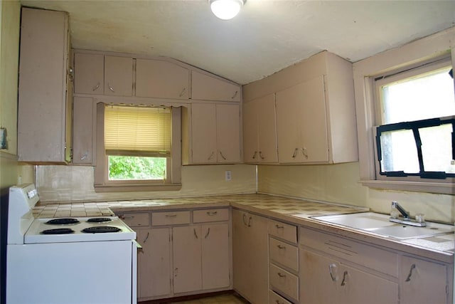1014 S Dewey Ave, Chandler, OK 74834 - kitchen with white electric range oven, healthy amount of natural light, a sink, light countertops, and vaulted ceiling