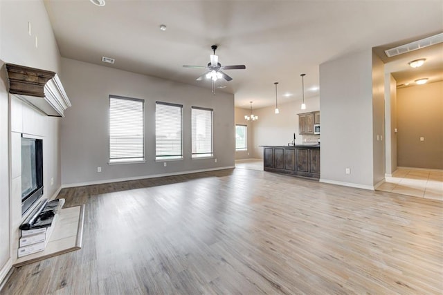 7720 Hawk Ln, Guthrie, OK 73044 - unfurnished living room with ceiling fan, baseboards, light wood-style flooring, and a glass covered fireplace