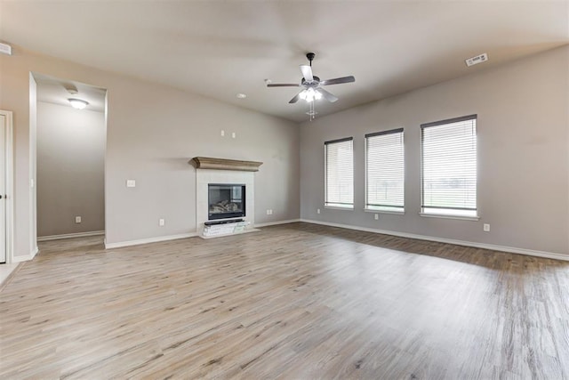 7720 Hawk Ln, Guthrie, OK 73044 - unfurnished living room with light wood-type flooring, a ceiling fan, baseboards, and a tile fireplace