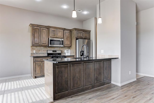 7720 Hawk Ln, Guthrie, OK 73044 - kitchen featuring stainless steel appliances, a sink, dark countertops, backsplash, and a peninsula