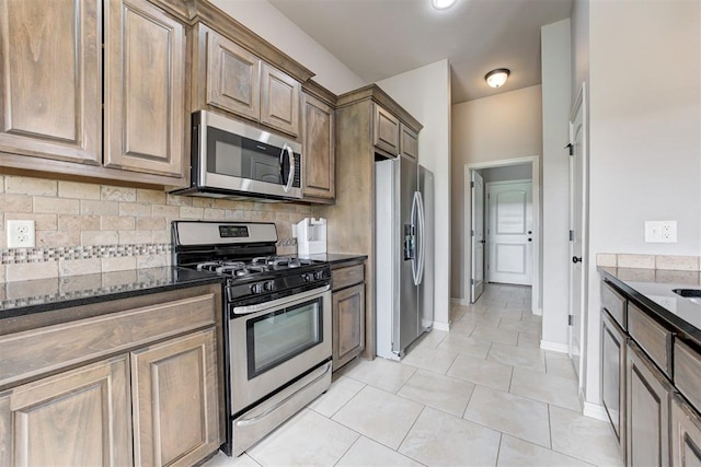 7720 Hawk Ln, Guthrie, OK 73044 - kitchen featuring stainless steel appliances, dark stone counters, tasteful backsplash, light tile patterned floors, and baseboards