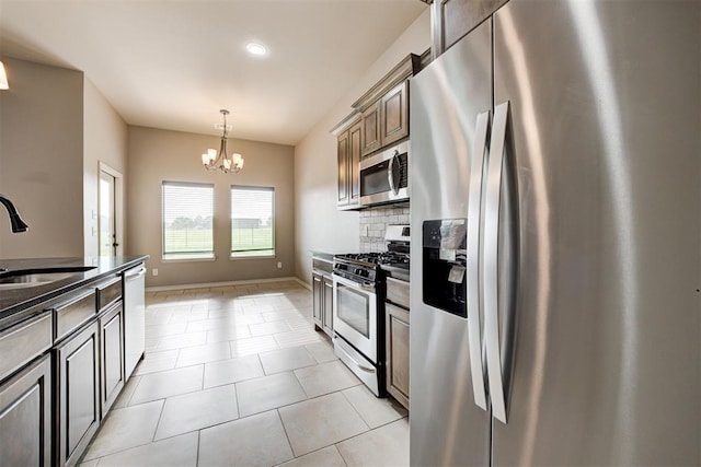 7720 Hawk Ln, Guthrie, OK 73044 - kitchen with stainless steel appliances, a sink, a chandelier, dark countertops, and tasteful backsplash