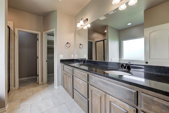 7720 Hawk Ln, Guthrie, OK 73044 - full bathroom featuring a stall shower, double vanity, a walk in closet, baseboards, and tile patterned flooring