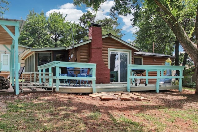 21306 E 10th St, Hinton, OK 73047 - back of property featuring a chimney, a wooden deck, a sunroom, and faux log siding