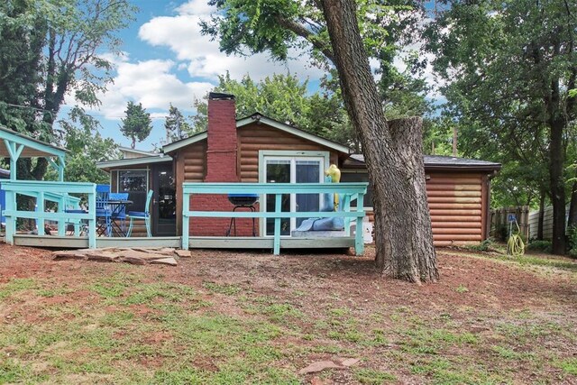 21306 E 10th St, Hinton, OK 73047 - back of property featuring log veneer siding, a chimney, a sunroom, and a deck