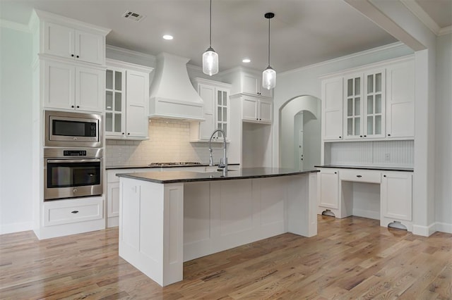 1108 Samantha Ln, Oklahoma City, OK 73160 - kitchen featuring appliances with stainless steel finishes, custom range hood, dark countertops, arched walkways, and backsplash
