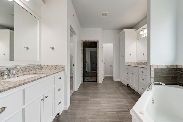 1108 Samantha Ln, Oklahoma City, OK 73160 - bathroom with two vanities, a jetted tub, and baseboards