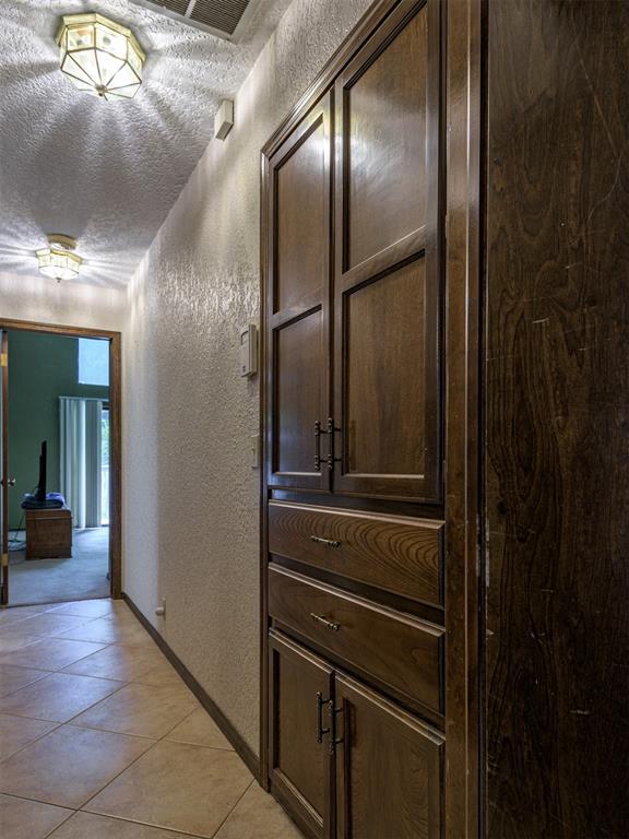 13501 Fox Hollow Rdg, Oklahoma City, OK 73131 - hallway with a textured wall, a textured ceiling, baseboards, and light tile patterned floors