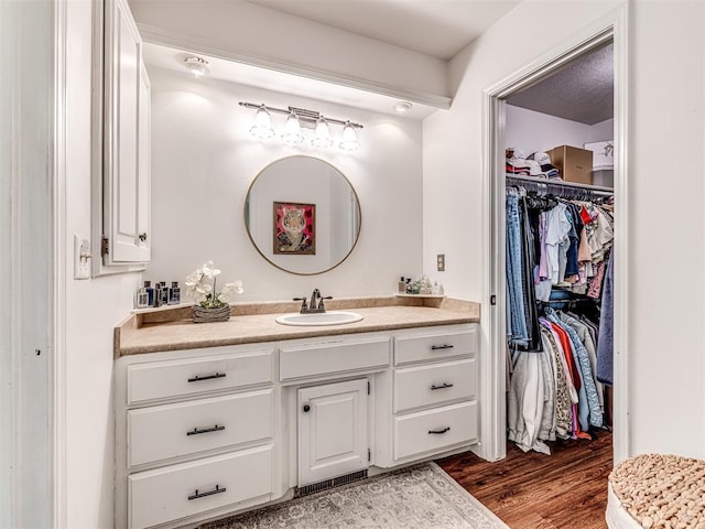 2009 Bella Vista Dr, Edmond, OK 73013 - bathroom featuring vanity, wood finished floors, and a spacious closet