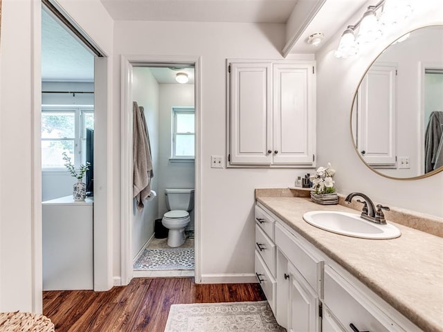 2009 Bella Vista Dr, Edmond, OK 73013 - bathroom featuring vanity, wood finished floors, baseboards, toilet, and healthy amount of natural light