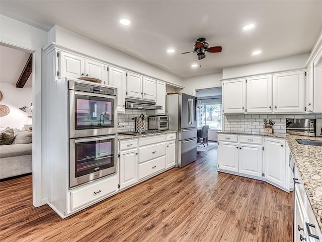 2009 Bella Vista Dr, Edmond, OK 73013 - kitchen featuring stainless steel appliances, light wood-style floors, ceiling fan, backsplash, and white cabinets
